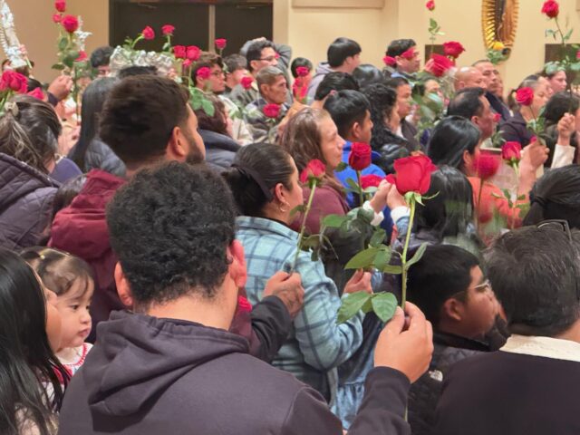 Parishioners holding their roses for blessing. Dialog photo/Cathy Rossi.
