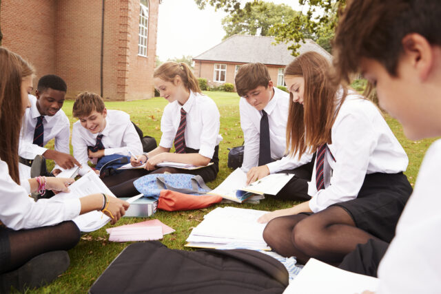 Teenage Students In Uniform Working On Project Outdoors